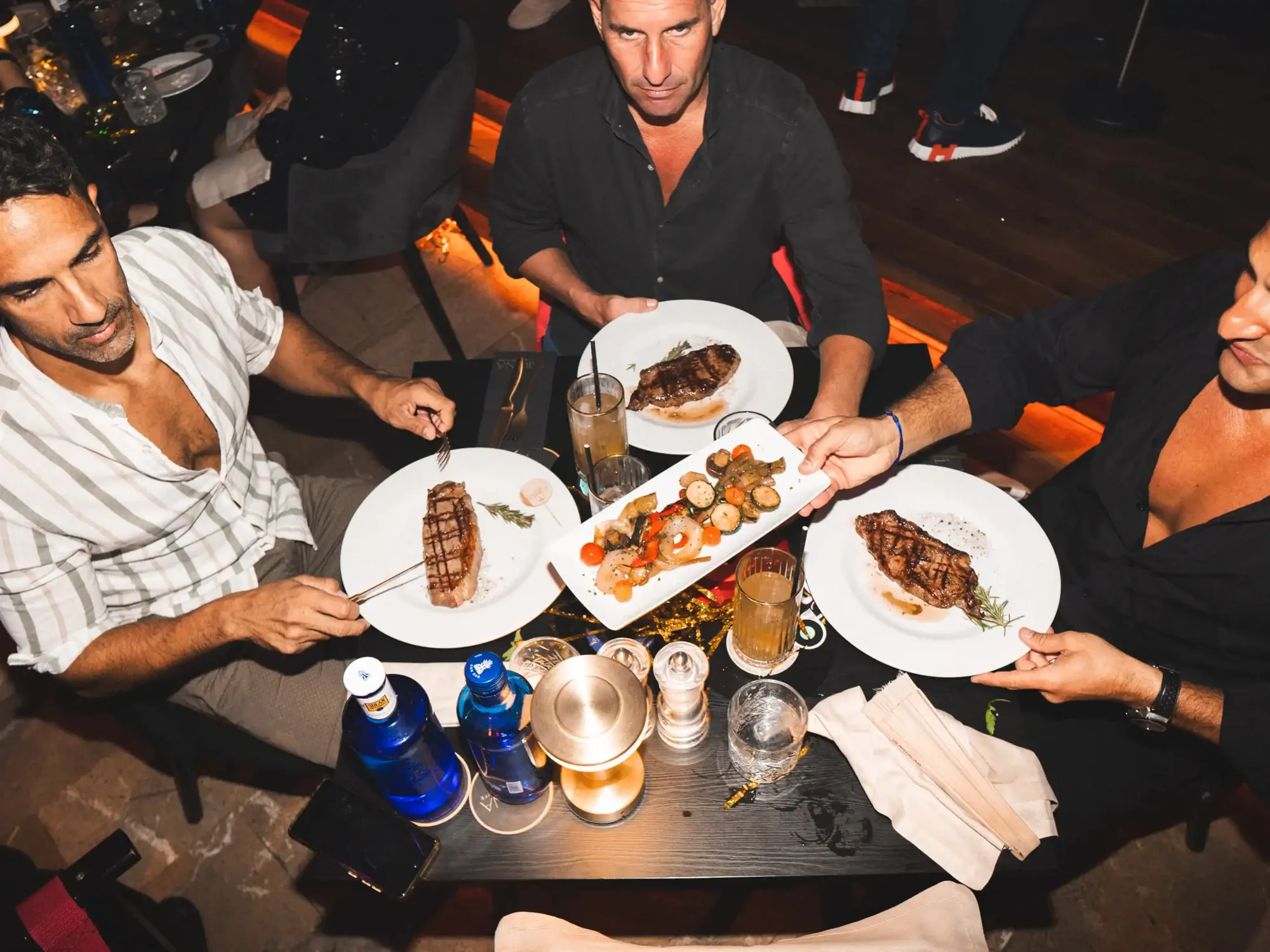 A table set with steaks and sharing plates, seen from above